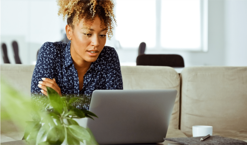 Young woman sitting on a couch looking at a laptop