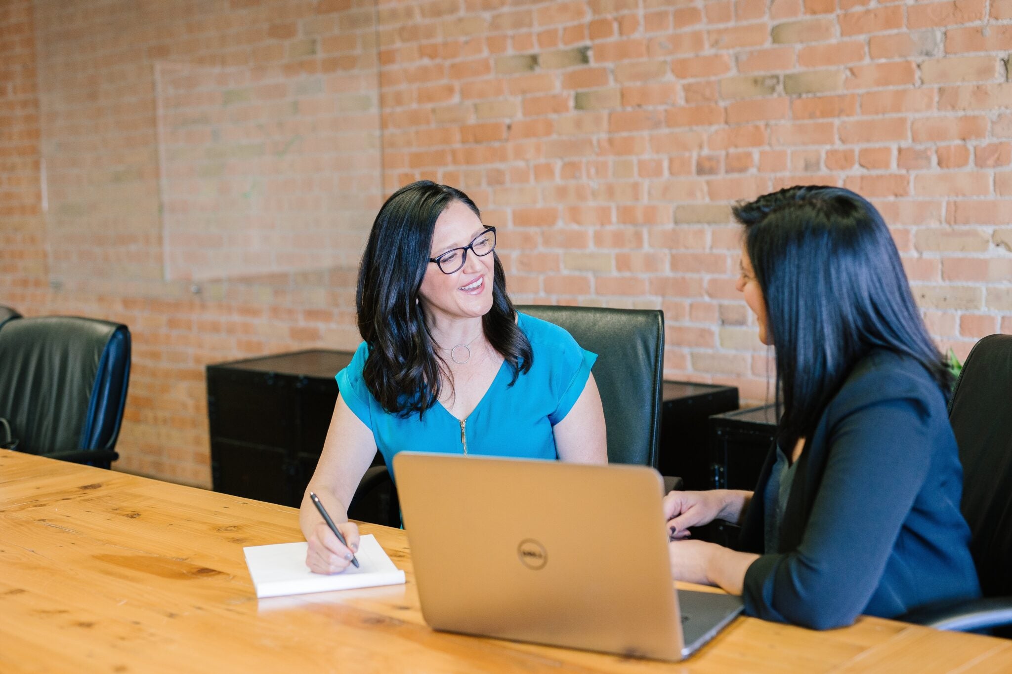 two women sitting at a laptop and smiling