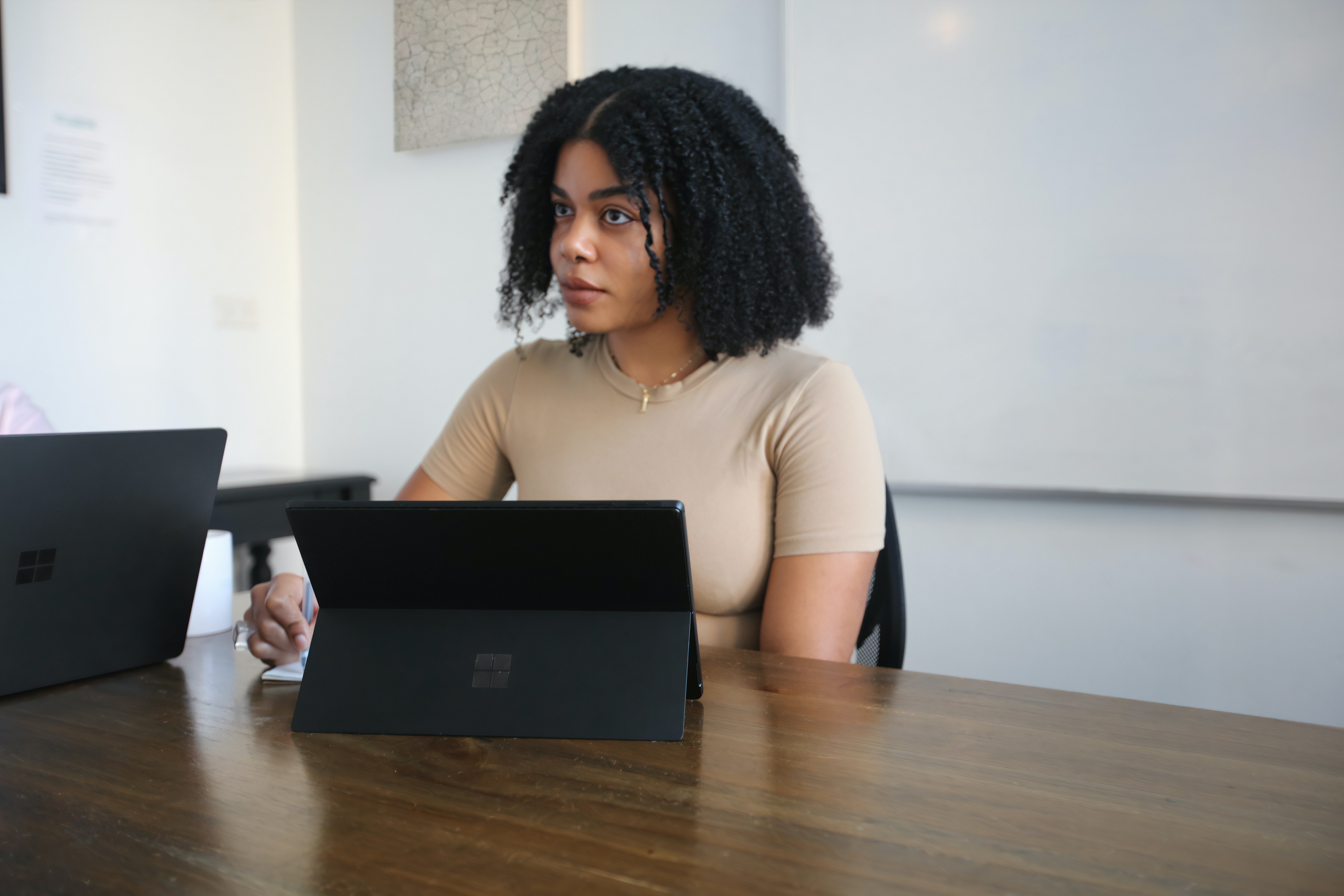 Young woman sitting at a table in front of a black tablet