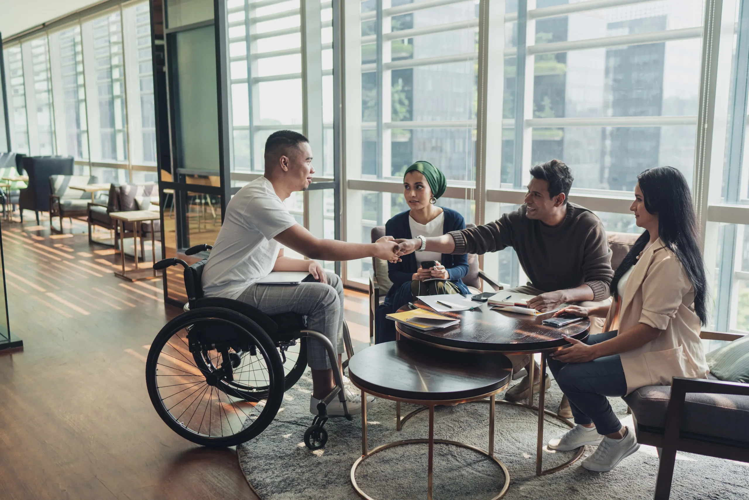 business professional wheelchair shakes colleague hand