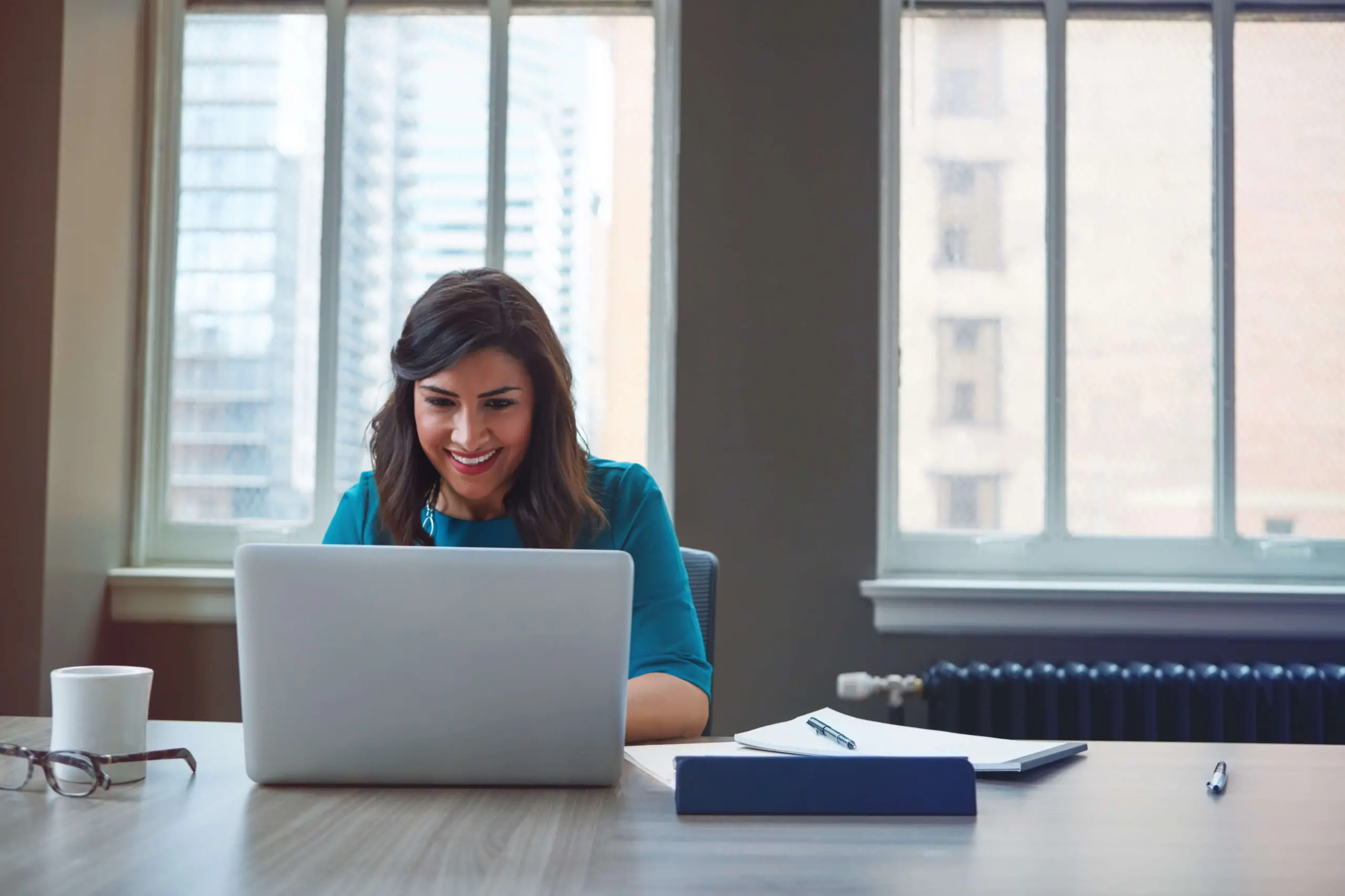 businesswoman works on laptop at conference room table