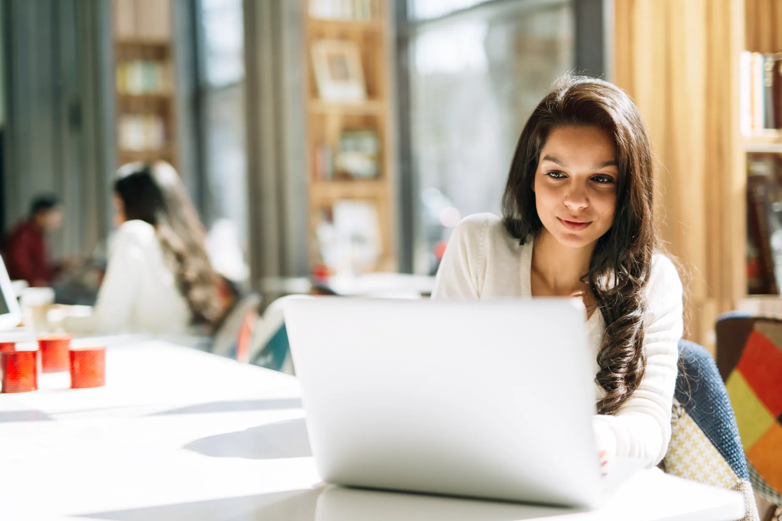 Brunette woman sitting at a desk looking intently at laptop